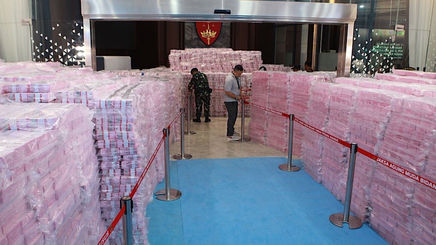 Petugas menata tumpukan uang penyelamatan keuangan negara dari hasil tindak pidana korupsi di Kejagung, Rabu (24/12/2025). (Bloomberg Technoz/Andre)