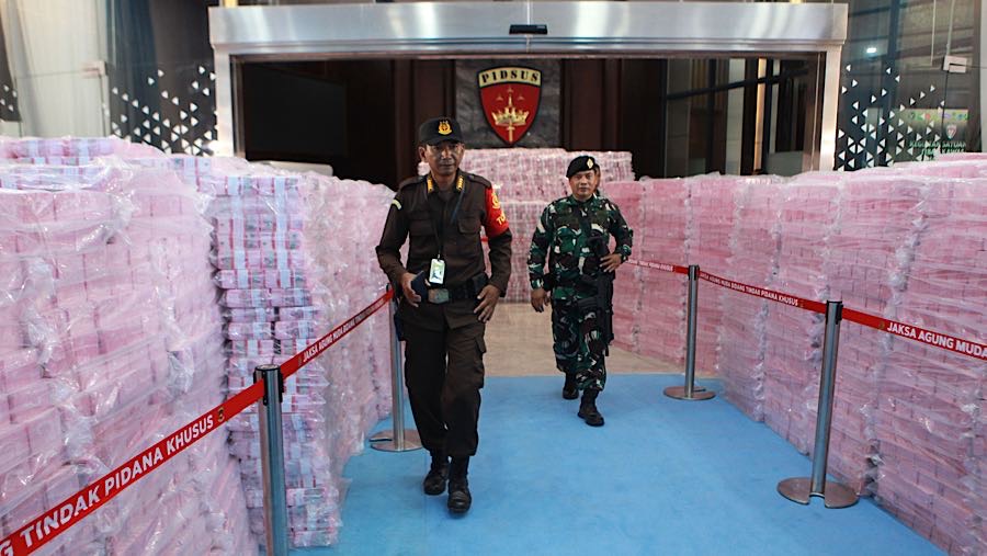 Petugas berjalan diantara tumpukan uang penyelamatan keuangan negara di Kejagung, Rabu (24/12/2025). (Bloomberg Technoz/Andre)