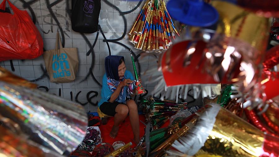 Pedagang membuat terompet yang akan dijualnya di kawasan Glodok, Jakarta, Selasa (30/12/2025). (Bloomberg Technoz/Andrean Kristianto)