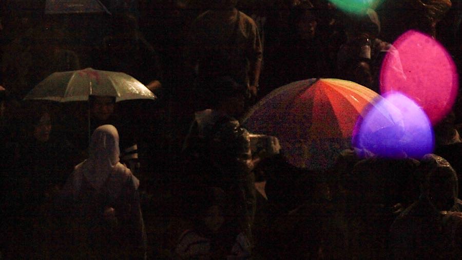 Dengan payung dan jas hujan, ribuan warga tetap menikmati rangkaian acara yang telah disiapkan. (Bloomberg Technoz/Andrean Kristianto)