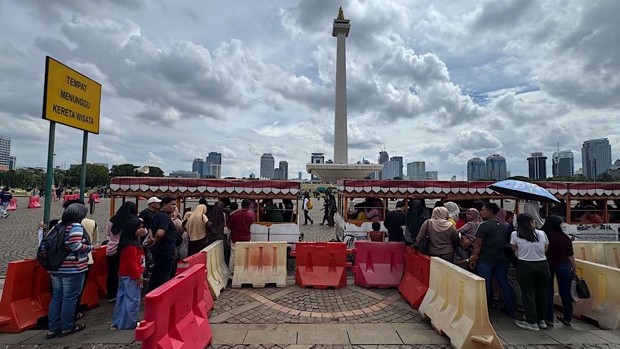 Pengunjung mengantre menaiki kereta wisata di kawasan Monas, Jakarta, Kamis (1/1/2026). (Bloomberg Technoz/Andrean Kristianto)