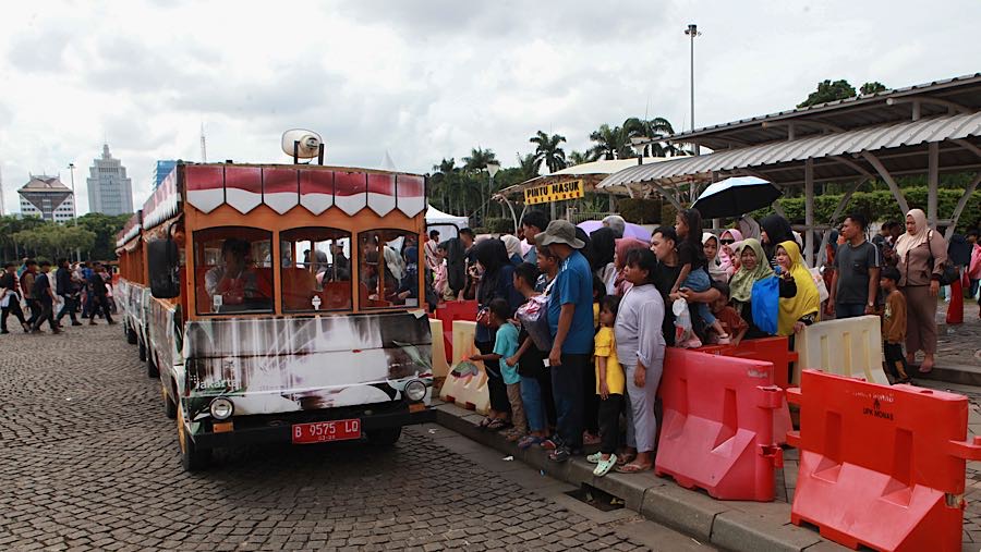 Pengunjung mengantre menaiki kereta wisata di kawasan Monas, Jakarta, Kamis (1/1/2026). (Bloomberg Technoz/Andrean Kristianto)