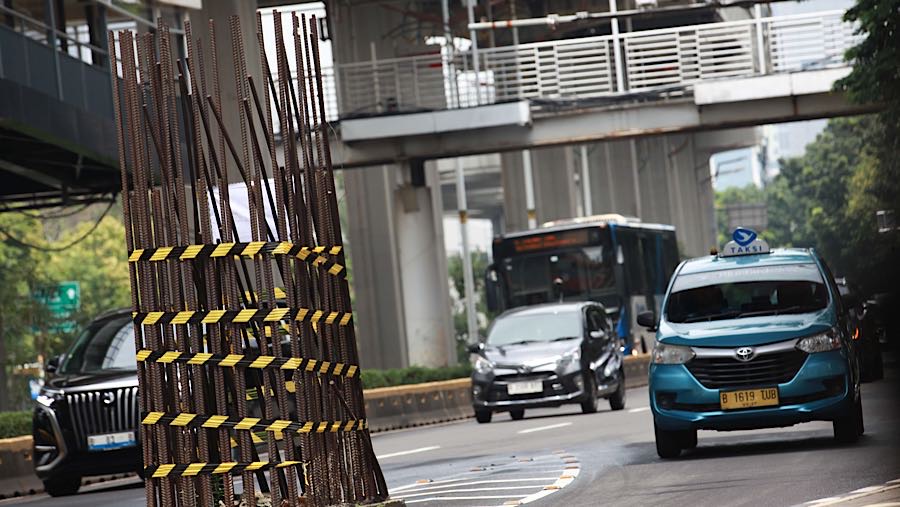 Kendaraan melintas di dekat tiang monorel yang mangkrak di Jalan Rasuna Said, Jakarta, Rabu (14/1/2026). (Bloomberg Technoz/Andrean Kristianto)
