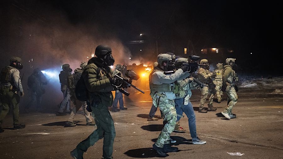 Aparat dan demonstran saling berhadapan di jalanan gelap, diselimuti awan gas air mata. (Victor J. Blue/Bloomberg)