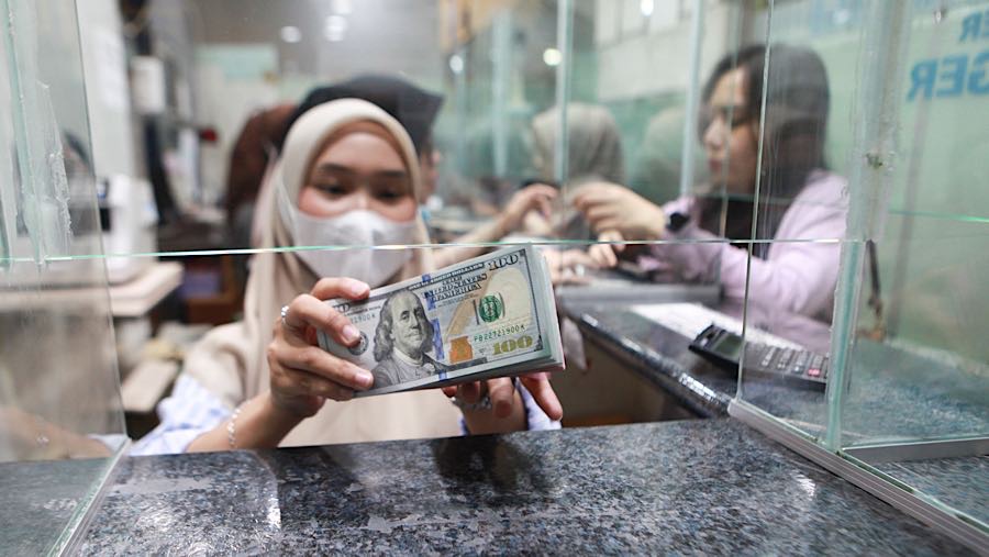 Pekerja menghitung uang dolar AS di tempat penukaran mata uang asing di Jakarta, Senin (19/1/2026). (Bloomberg Technoz/ Andrean Kristianto)
