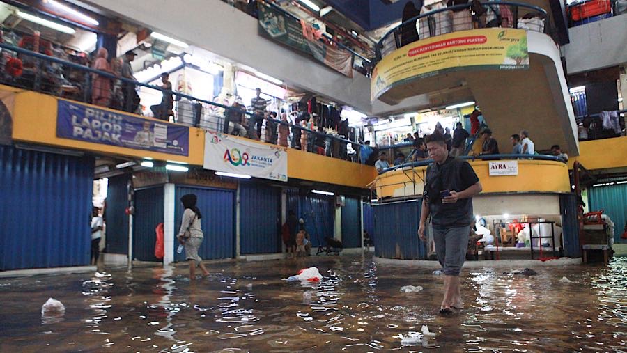 Pengunjung melewati genangan air di Pasar Cipulir, Jakarta, Jumat (23/1/2026). (Bloomberg Technoz/Andrean Kristianto)