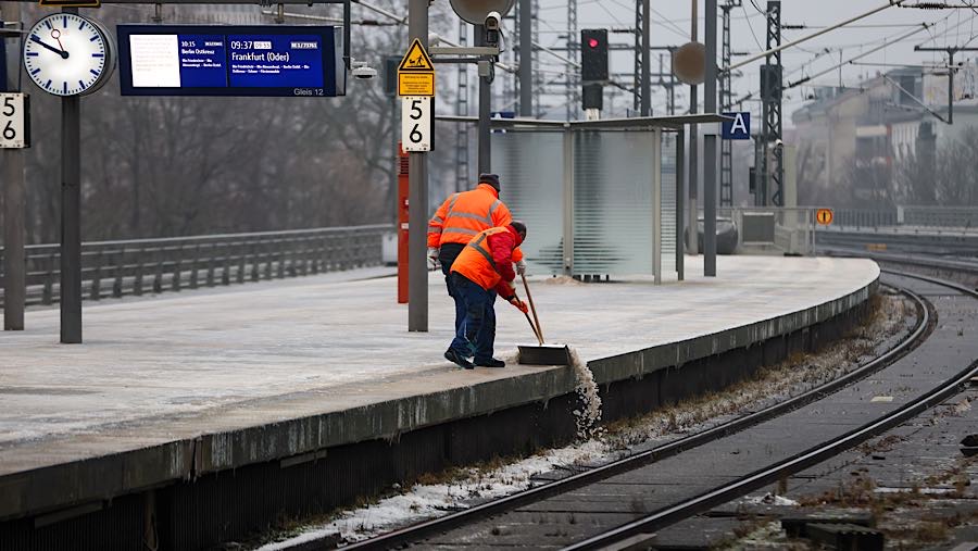 Para pekerja membersihkan salju dari peron di stasiun kereta api Berlin Central di Berlin, Jerman, Senin (26/1/2026). (Krisztian Bocsi/Bloomberg)