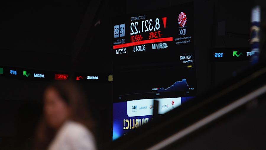 Karyawan melintas di depan layar pergerakan harga saham (IHSG) di Bursa Efek Indonesia (BEI), Rabu (28/1/2026). (Bloomberg Technoz/Andrean Kristianto)