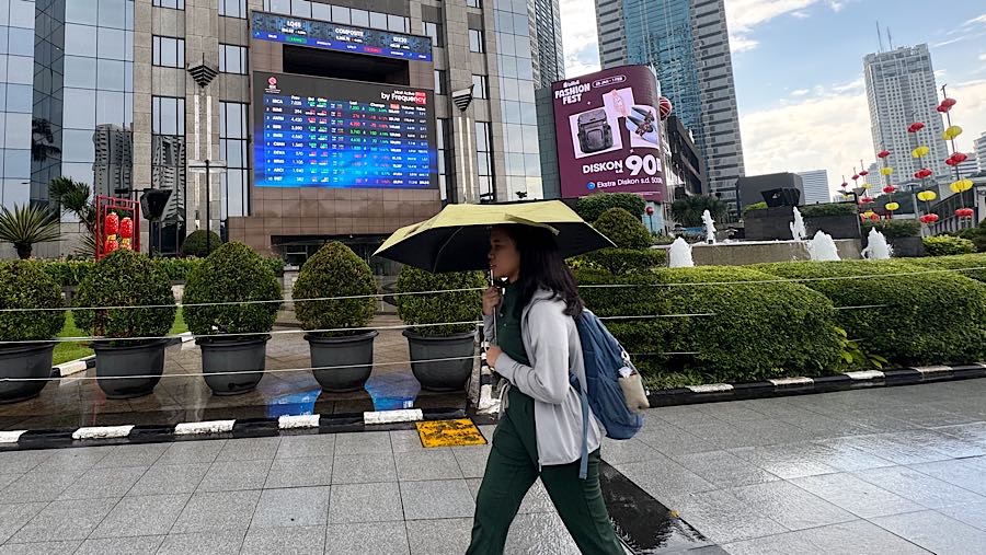 Warga melintas di depan layar pergerakan harga saham (IHSG) di Bursa Efek Indonesia (BEI), Kamis (29/1/2026). (Bloomberg Technoz/Andrean Kristianto)
