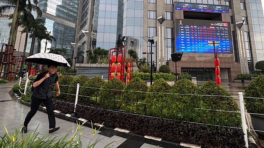 Warga melintas di depan layar pergerakan harga saham (IHSG) di Bursa Efek Indonesia (BEI), Kamis (29/1/2026). (Bloomberg Technoz/Andrean Kristianto)