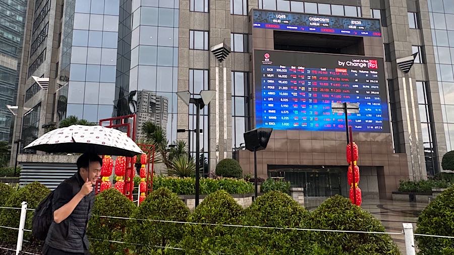 Warga melintas di depan layar pergerakan harga saham (IHSG) di Bursa Efek Indonesia (BEI), Kamis (29/1/2026). (Bloomberg Technoz/Andrean Kristianto)
