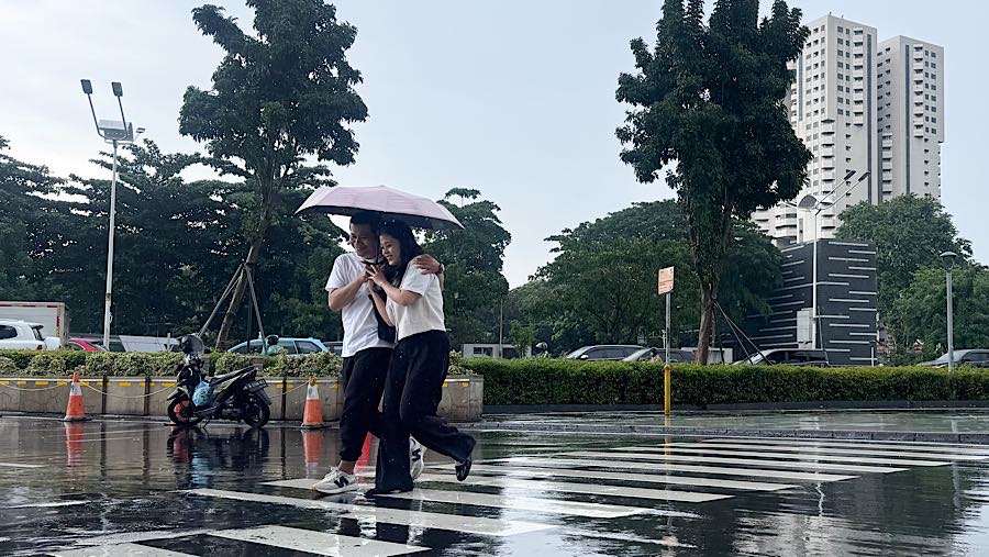 Warga menggunakan payung saat hujan di Jakarta, Kamis (29/1/2026). (Bloomberg Technoz/Andrean Kristianto)
