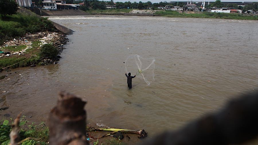 Warga menjaring ikan di Sungai Cisadane, Tangerang, Rabu (11/2/2026). (Bloomberg Technoz/Andrean Kristianto)