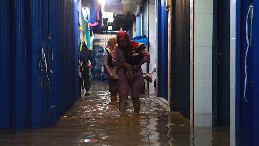 Pengunjung melewati genangan air di Pasar Cipulir, Jakarta Selatan, Jumat (20/2/2026). (Bloombeg Technoz/Andrean Kristianto)