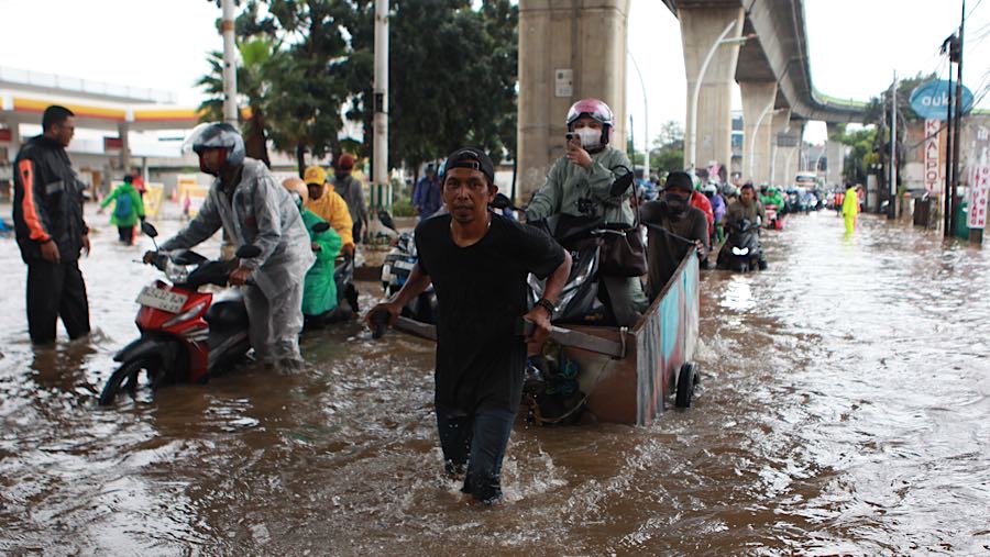 Ada juga warga yang memanfaatkan jasa ojek gerobak untuk melewati genangan air tersebut. (Bloombeg Technoz/Andrean Kristianto)