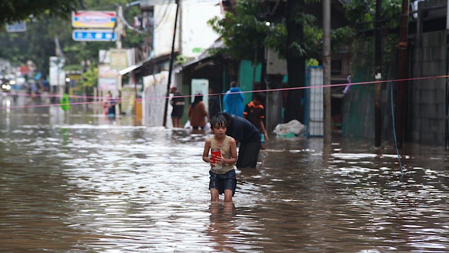 Anak bermain banjir di Jalan Swadarma Raya, Jumat (20/2/2026). (Bloombeg Technoz/Andrean Kristianto)