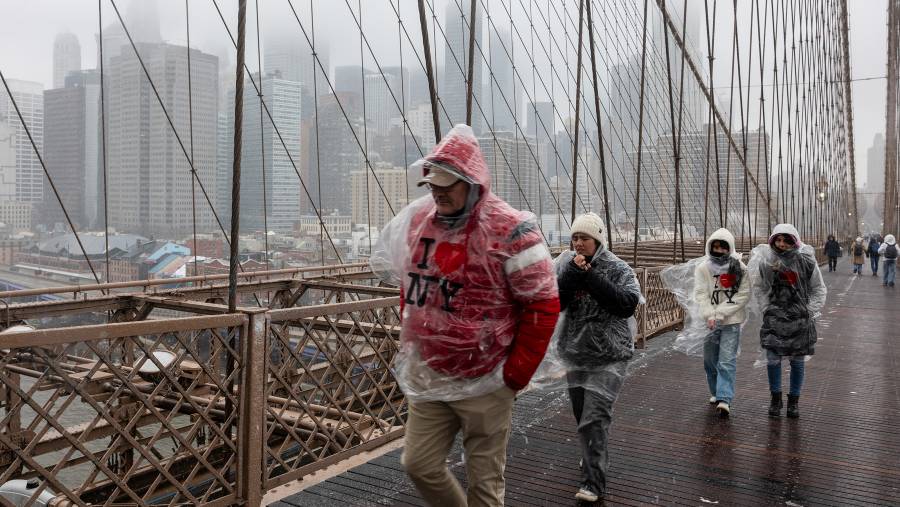 Para pejalan kaki berjalan melintasi Jembatan Brooklyn saat salju mulai turun di New York pada 22 Februari. (Sumber: Bloomberg)