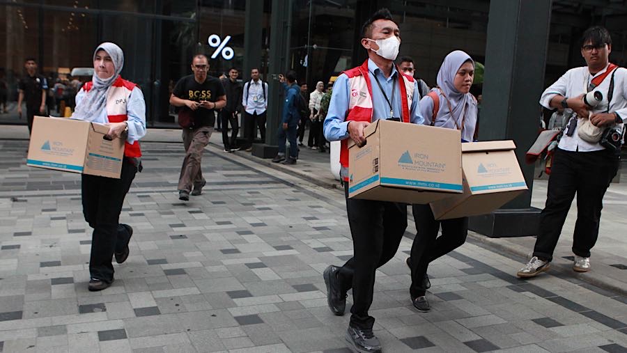 Petugas DPJK OJK membawa barang hasil sitaan penggeledahan di kantor sekuritas di Gedung Treasury Tower, Rabu (4/3/2026). (Bloomberg Technoz/Andrean)