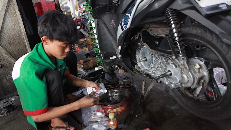 Mekanik memperbaiki sepeda motor di bengkel kawasan Pasar Minggu, Jakarta Selatan, Selasa (10/3/2026). (Bloomberg Technoz/Andrean Kristianto)