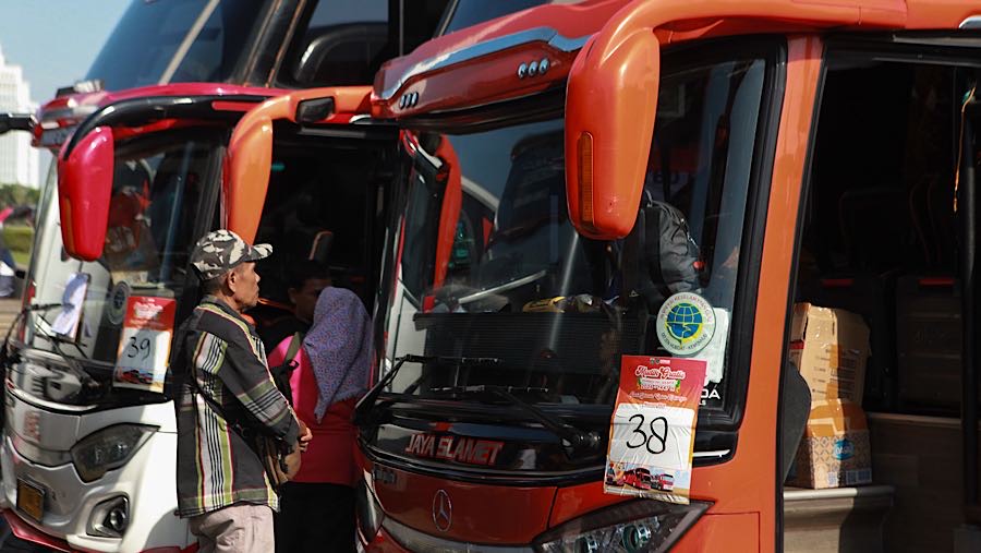 Pengemudi berdoa di depan busnya yang akan membawa peserta mudik gratis di Lapangan Monas, Selasa (17/3/2026). (Bloomberg Technoz/Andrean Kristianto)
