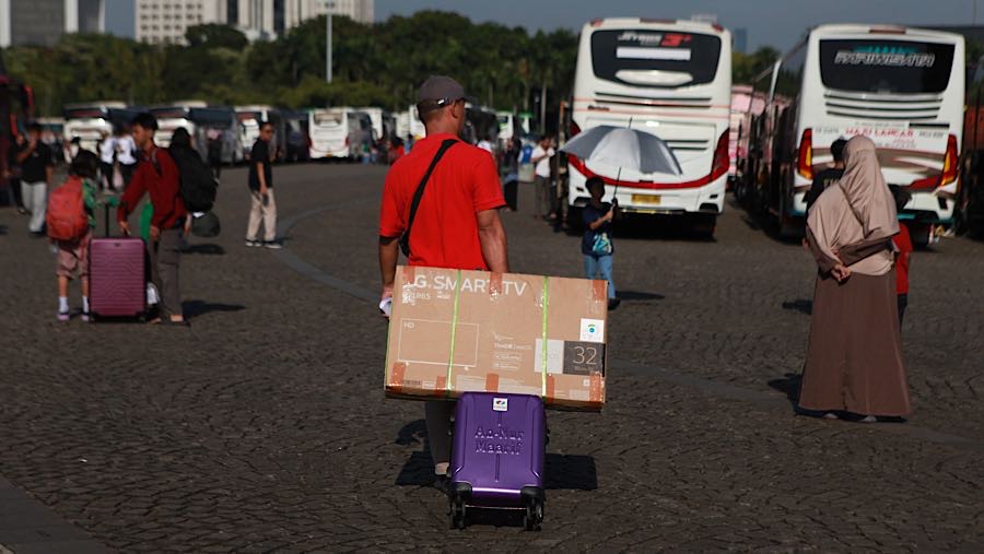 Warga tampak ceria meskipun harus berjalan cukup jauh menuju bus di bawah terik matahari pagi. (Bloomberg Technoz/Andrean)