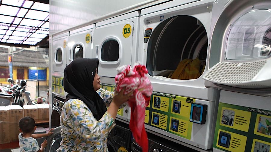 Warga memasukan pakaian kotor ke dalam mesin cuci di salah satu usaha cuci pakaian di Jakarta, Senin (30/3/2026). (Bloomberg Technoz/Andrean K)