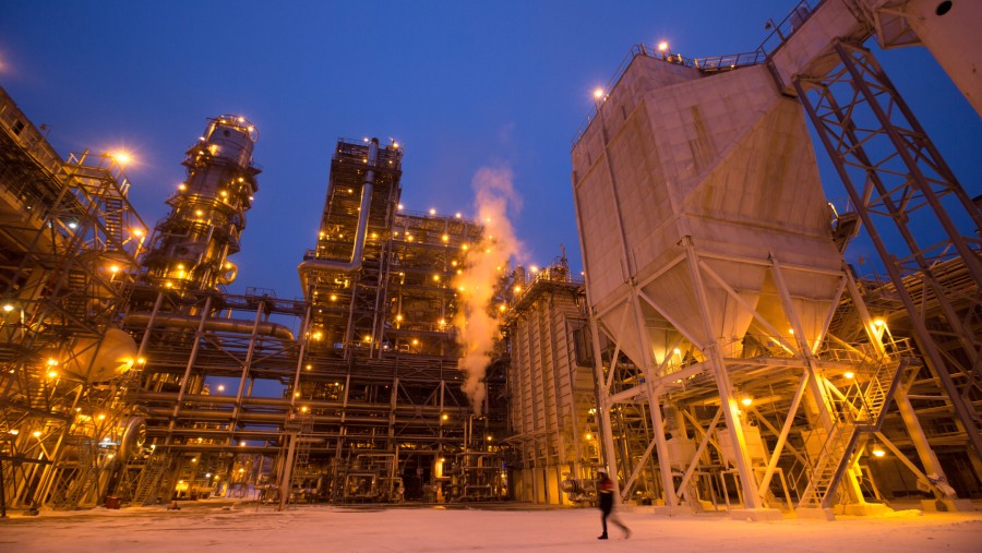 Kawyawan melintasi salju melewati menara pemecah minyak bumi di kilang minyak Lukoil-Nizhegorodnefteorgsintez di Rusia./Bloomberg-Andrey Rudakov