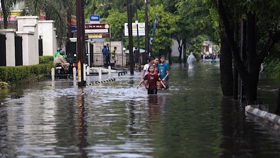 Warga melintasi banjir di jalan Siaga Raya, Jakarta Selatan, Selasa (21/4/2026). (Bloomberg Technoz/Andrean Kristianto)