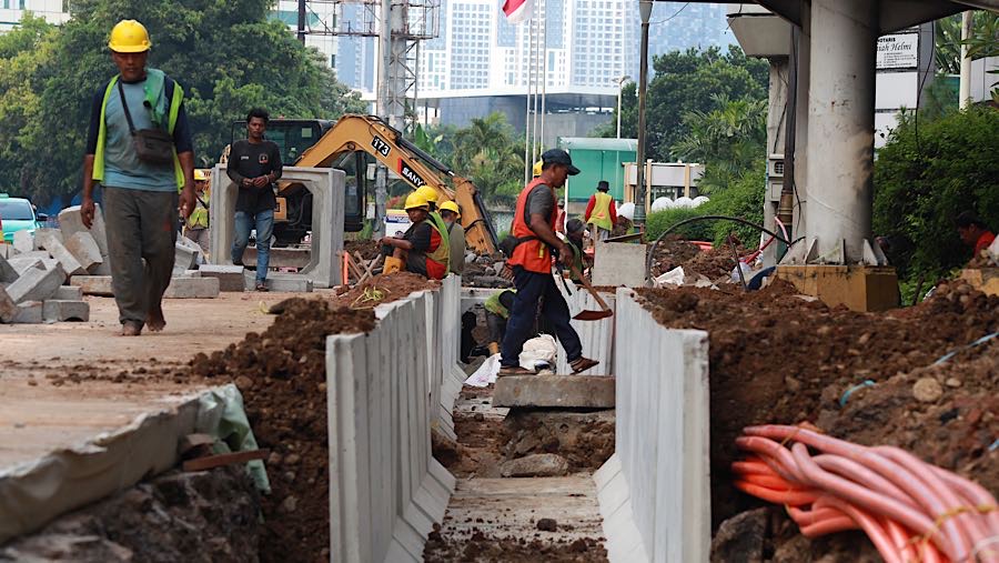 Pekerja menyelesaikan proyek revitalisasi trotoar di Jalan H.R. Rasuna Said, Jakarta, Rabu (22/4/2026). (Bloomberg Technoz/Andrean Kristianto)