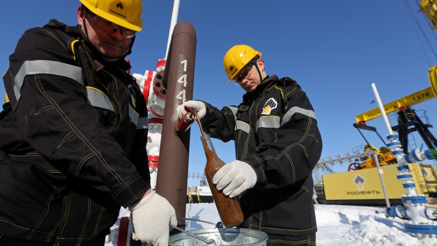 Pekerja menggunakan botol untuk mengambil sampel minyak mentah di anjungan sumur ganda yang dioperasikan oleh Rosneft PJSC di Rusia./Bloomberg