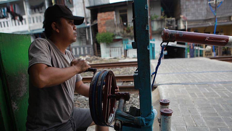 Iwan menjaga palang pintu tidak resmi di perlintasan kereta api sebidang di Tebet Timur, Kamis (30/4/2026). (Bloomberg Technoz/Andrean Kristianto)