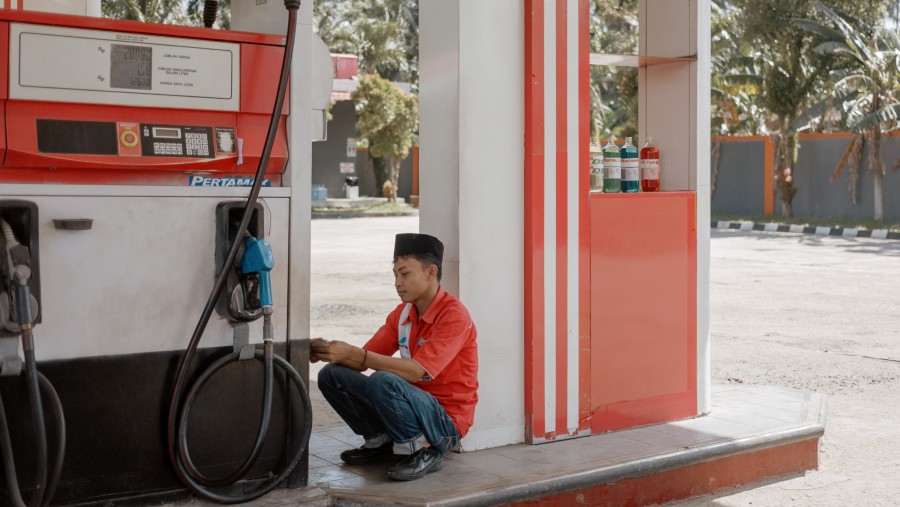 Seorang pekerja duduk di dekat pompa bahan bakar di sebuah SPBU PT Pertamina di Bihar, Provinsi Lampung, Indonesia./Bloomberg-Muhammad Fadli