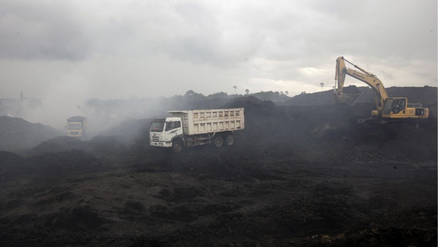 Truk dan ekskavator di tengah asap di tambang batu bara terbuka PT Exploitasi Energi Indonesia di Palaran, Kalimantan Timur./Bloomberg-Dadang Tri