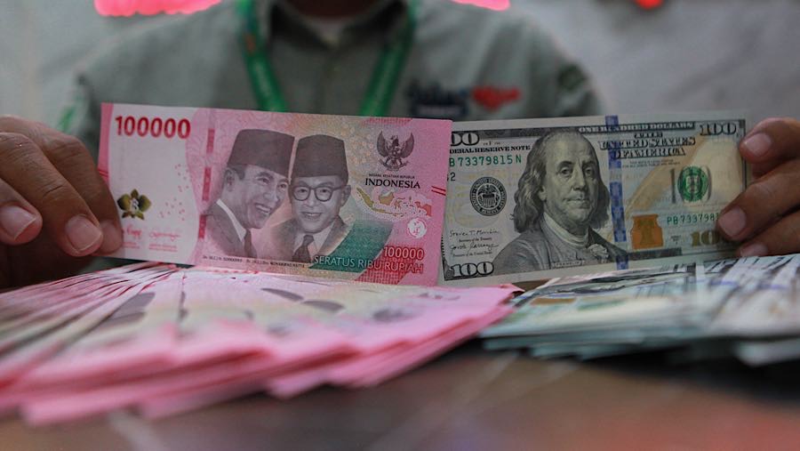 Karyawan menunjukkan mata uang rupiah dan dolar AS di tempat penukaran mata uang, Jakarta, Selasa (12/5/2026). (Bloomberg Technoz/Andrean Kristianto)