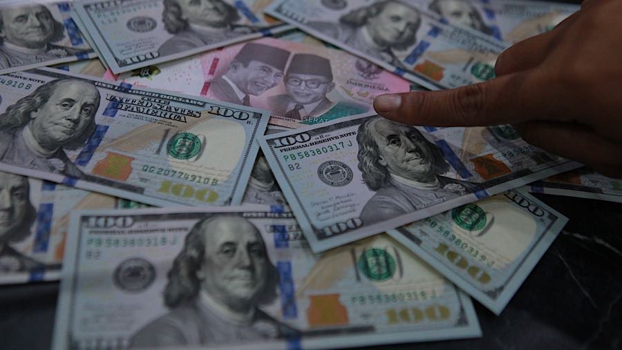 Karyawan menunjukkan mata uang rupiah dan dolar AS di tempat penukaran mata uang, Jakarta, Selasa (12/5/2026). (Bloomberg Technoz/Andrean Kristianto)
