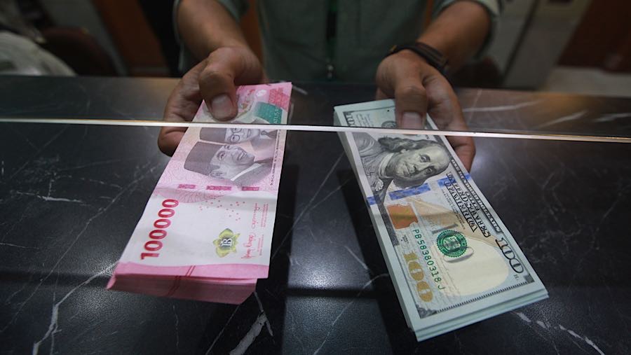 Karyawan memegang mata uang rupiah dan dolar AS di tempat penukaran mata uang, Jakarta, Selasa (12/5/2026). (Bloomberg Technoz/Andrean Kristianto)