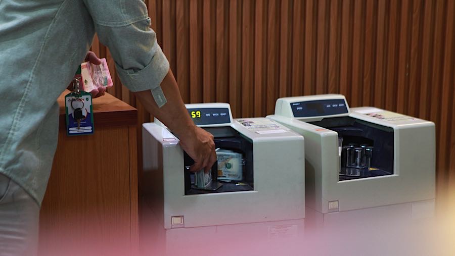 Karyawan menghitung mata uang dolar AS di tempat penukaran mata uang, Jakarta, Selasa (12/5/2026). (Bloomberg Technoz/Andrean Kristianto)