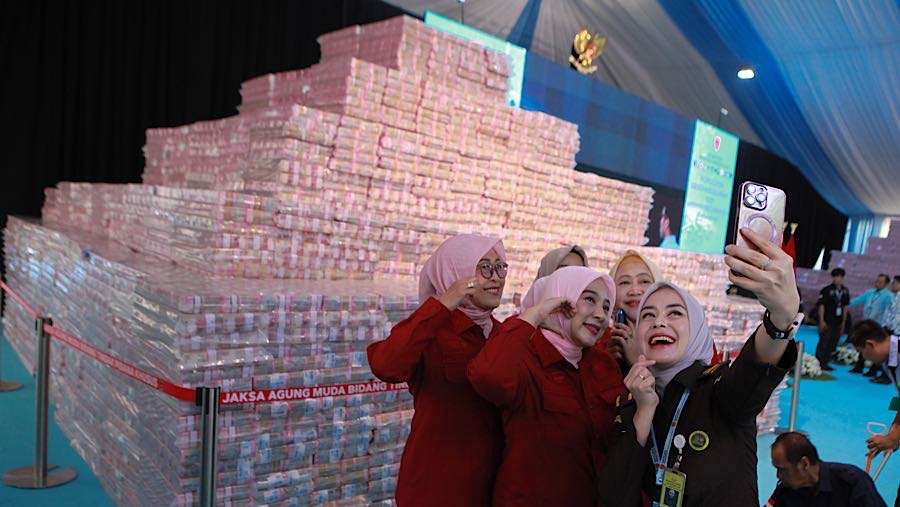 Mereka yang datang berfoto bersama maupun sendiri dengan latar gunungan uang yang akan diserahkan ke kas negara (Bloomberg Technoz/Andrean Kristianto)