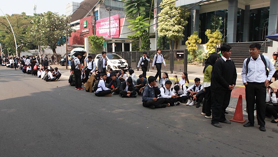 Deretan anak muda mengenakan kemeja putih dan celana hitam terlihat mengular di trotoar sepanjang sekitar 80 meter. (Bloomberg Technoz/Andrean K)