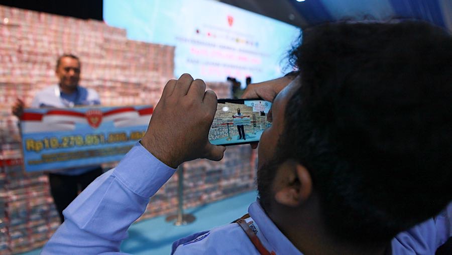 Tak sedikit yang datang dalam acara tersebut memanfaatkan tumpukan uang itu untuk berfoto. (Bloomberg Technoz/Andrean Kristianto)