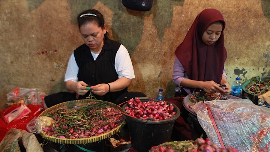 Pekerja mengupas bawang merah di Pasar Induk Kramat Jati, Jumat (22/6/2026). (Bloomberg Technoz/Andrean Kristianto)