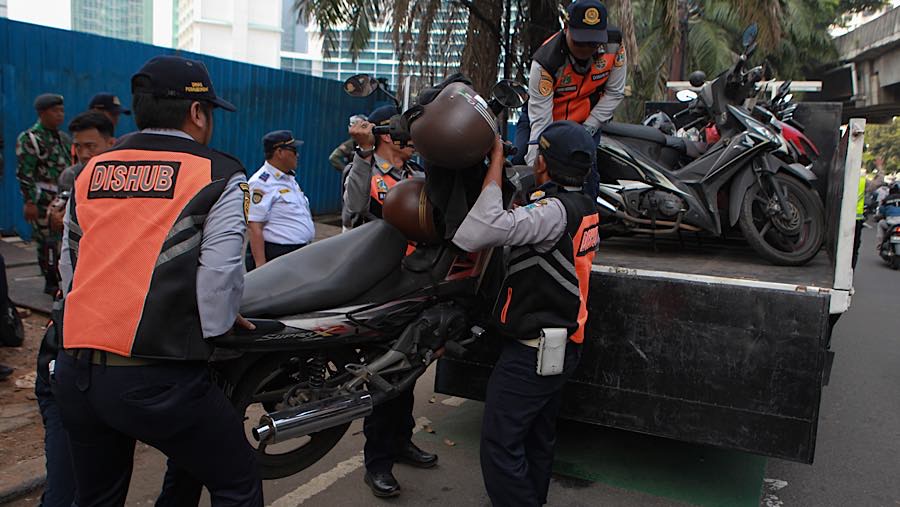 Petugas mengangkut sepeda motor saat penertiban parkir liar di kawasan K.H. Mas Mansyur, Jakarta Pusat, Kamis (10/6/2026). (Bloomberg Technoz/Andrean)