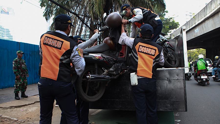 Petugas mengangkut sepeda motor saat penertiban parkir liar di kawasan K.H. Mas Mansyur, Jakarta Pusat, Kamis (10/6/2026). (Bloomberg Technoz/Andrean)