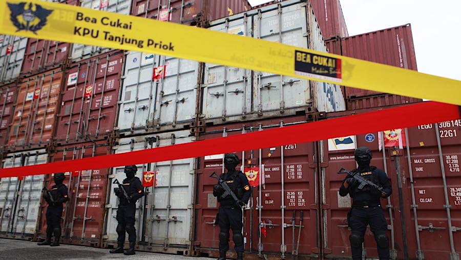 Petugas berjaga di depan peti kemas berisi balpres sitaan di Pelabuhan Tanjung Priok, Jakarta, Selasa, (23/6/2026). (Bloomberg Technoz/Andrean K)