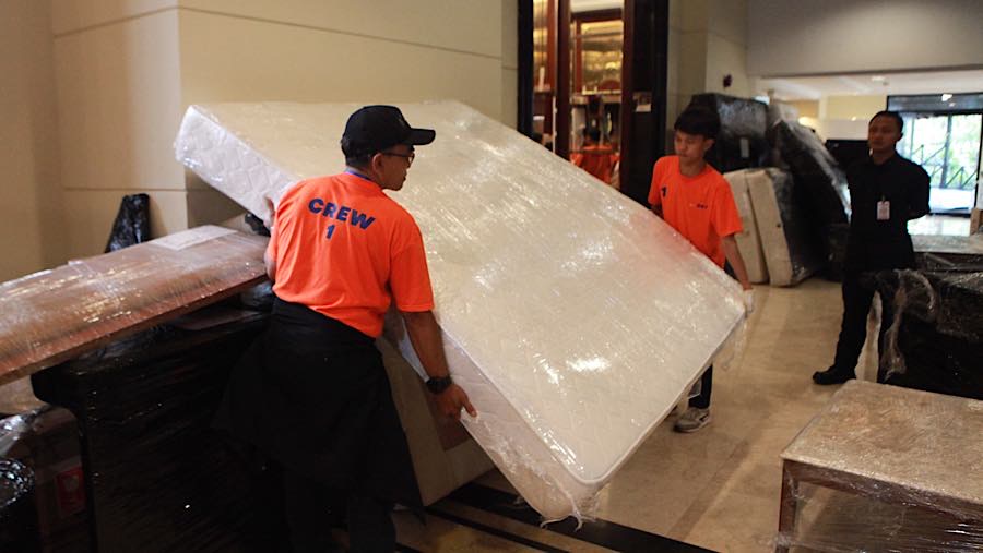 Puluhan petugas pengangkut barang menggotong barang-barang yang berada di dalam Hotel Sultan. (Bloomberg Technoz/Andrean Kristianto)