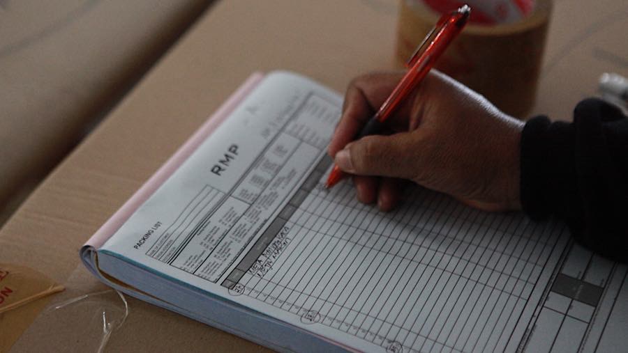 Sejumlah barang yang selesai dikemas lalu didata oleh pekerja yang bertugas. (Bloomberg Technoz/Andrean Kristianto)