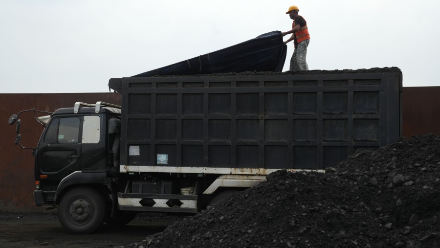 Seorang pekerja menutupi bagian atas truk yang penuh muatan batu bara di Pelabuhan Cirebon, Jawa Barat, Indonesia./Bloomberg-Dimas Ardian