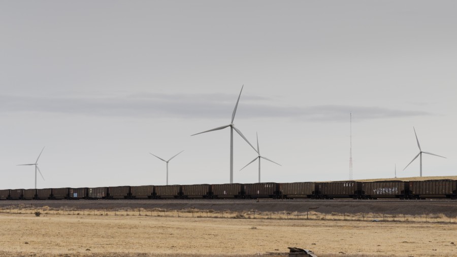 Kereta api pengangkut batu bara di depan turbin angin di dekat Encino, New Mexico. (Minesh Bacrania/Bloomberg)