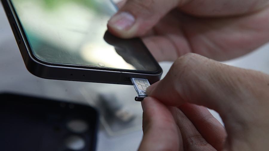 Petugas membantu pelanggan saat memasukkan kartu sim ke hp di Jakarta, Rabu (1/6/2026). (Bloomberg Technoz/Andrean Kristianto)