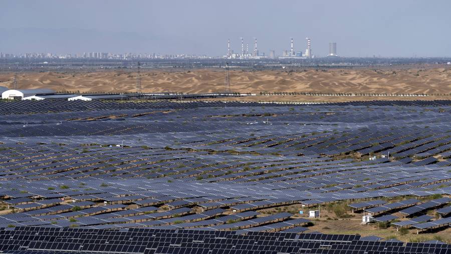 Panel surya di pusat energi bersih Dalad Banner, dengan infrastruktur PLTU terlihat di balik bukit-bukit pasir gurun. (Qilai Shen/Bloomberg)